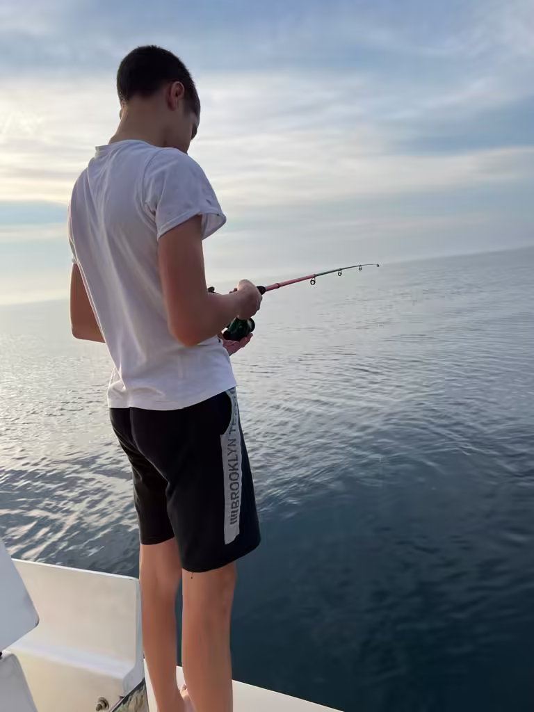 Teen angler casting into a glassy sea