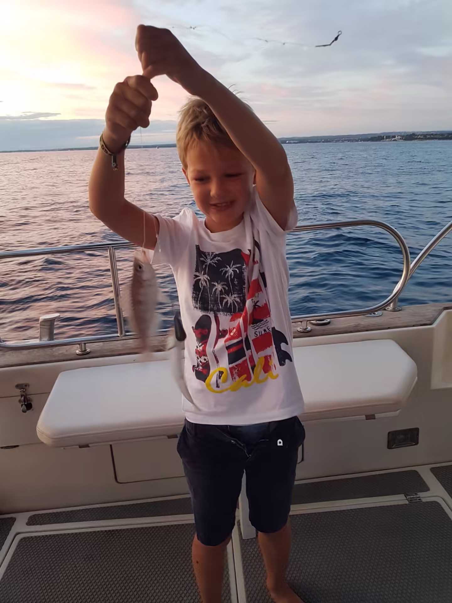 Young guest proud of his sunset catch