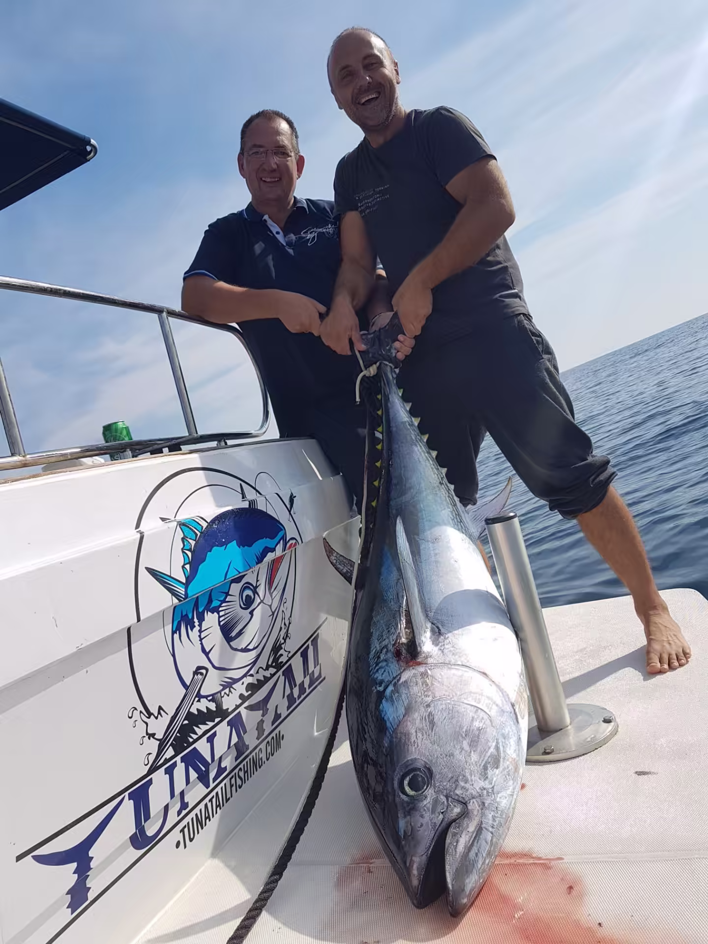 Guests posing with a Bluefin tuna next to the boat
